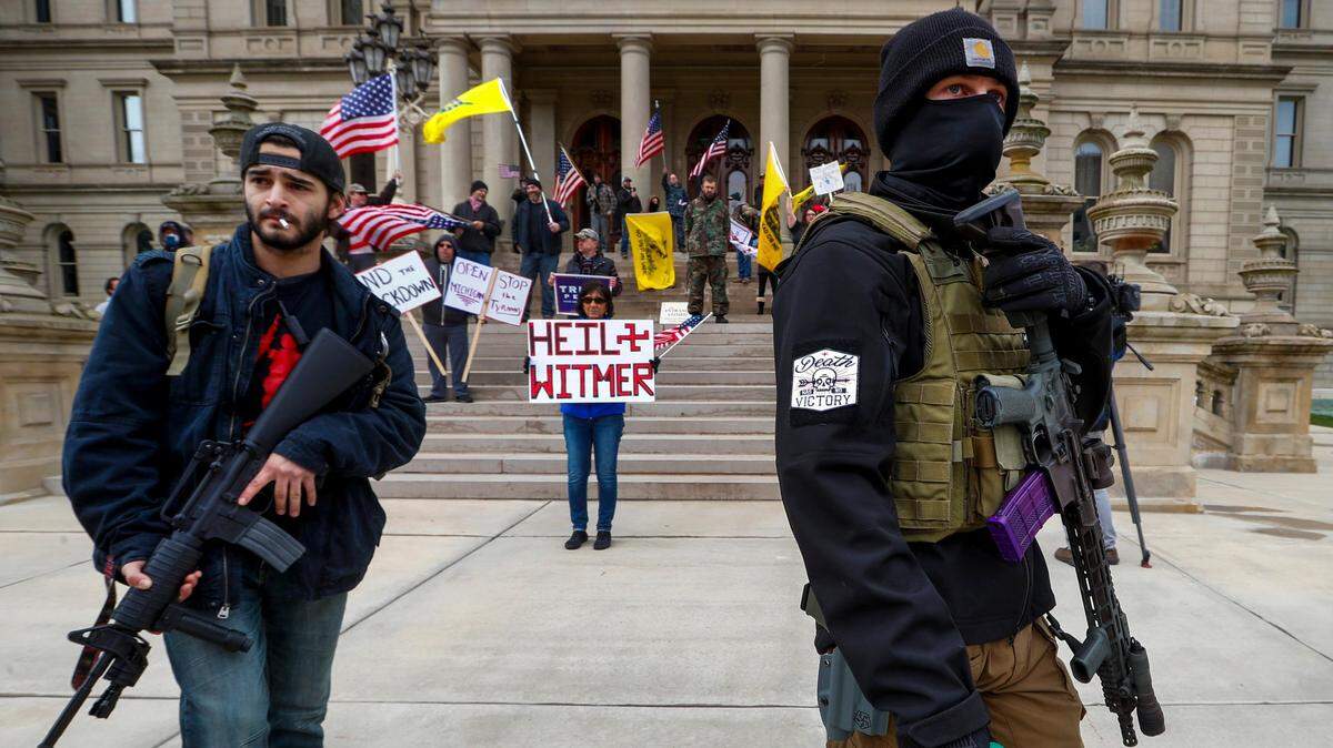 Hombres armados con rifles caminan frente al Capitolio estatal el 15 de abril de 2020, en Lansing, Michigan.