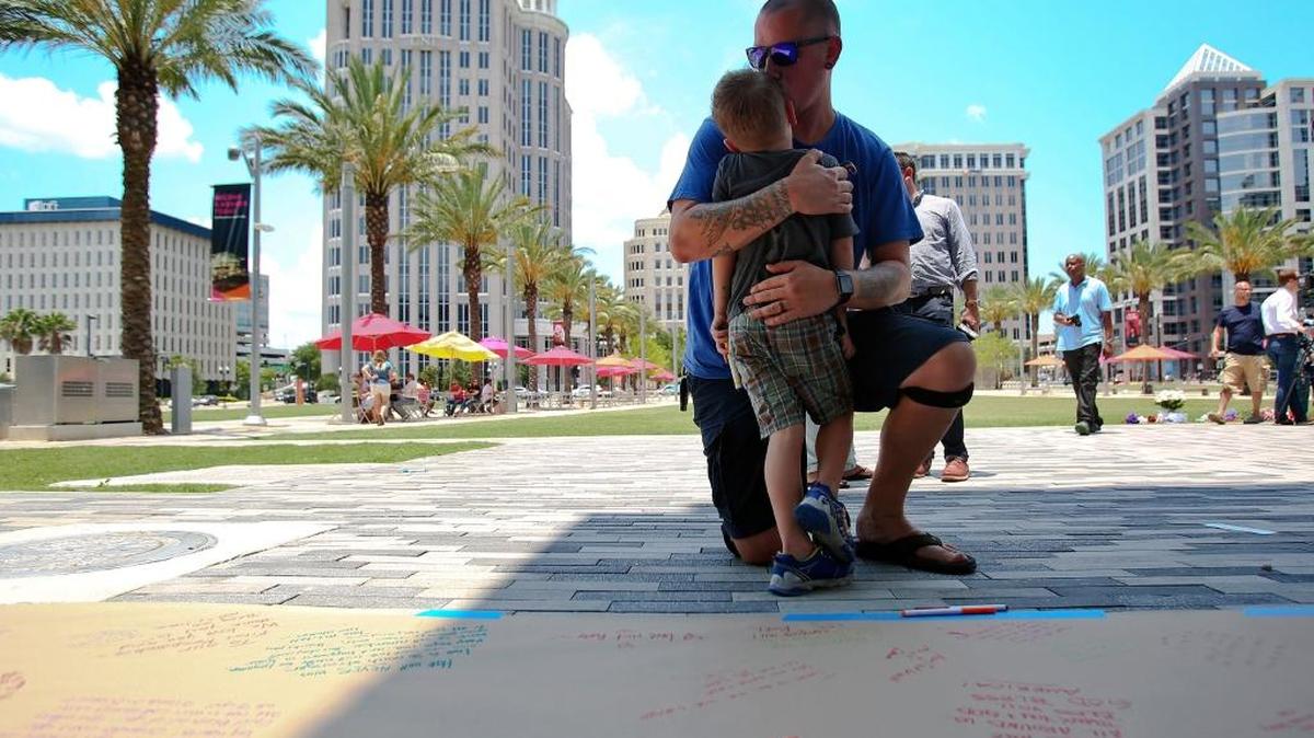 Tim Christofore con su hijo Jude, de 4 años, en un memorial improvisado para las 49 víctimas de la masacre en el club Pulse en Orlando. Las ofrendas se colocaron en el exterior del Dr. Phillips Performing Arts Center, en Orlando. Christofore recordó a su amigo Shane Tomlinson, que pereció en el tiroteo.