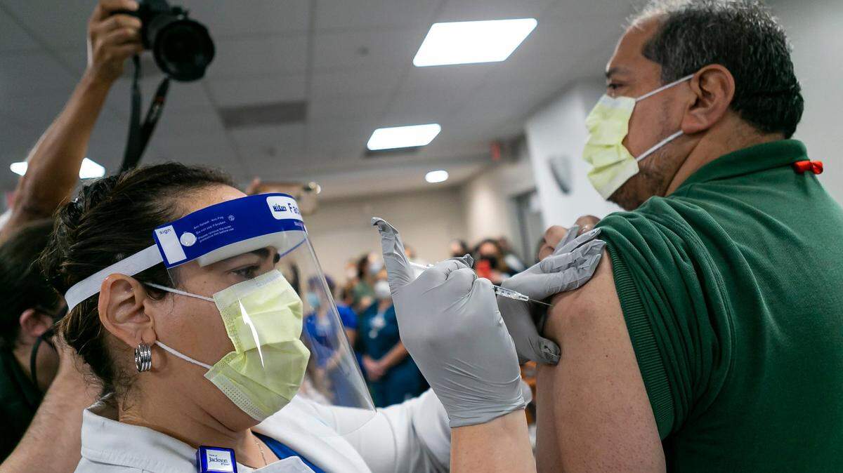 Environmental Service Worker Armando Acosta receives the Pfizer BioNTech COVID-19 Vaccine at Jackson Memorial Hospital in Miami, Florida on Tuesday, December 15, 2020.