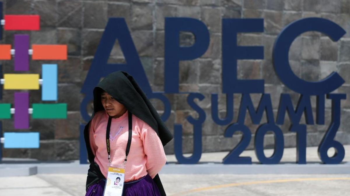 Una mujer camina frente al letrero del Foro de Cooperación Económica Asia-Pacífico, en el Museo Nacional de Lima, el 16 de noviembre.