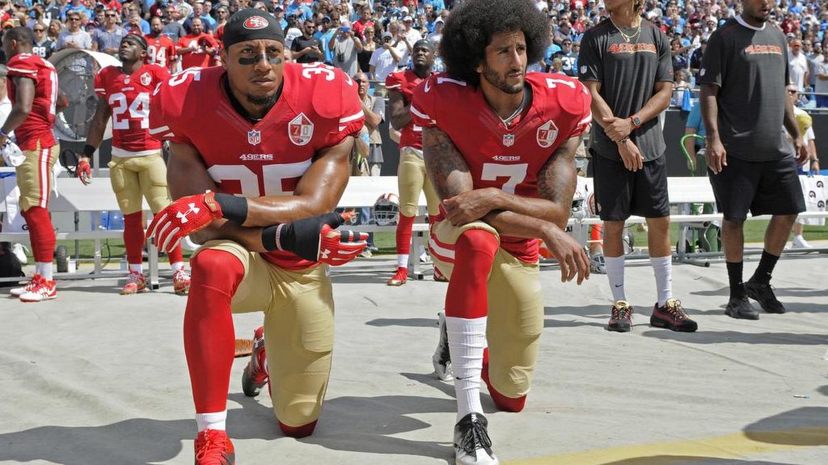 Colin Kaepernick (der.) y Eric Reid, jugadores de los San Francisco 49ers, se arrodillan mientras tocan el himno nacional antes de un partido en Charlotte, Carolina del Norte, el domingo pasado.