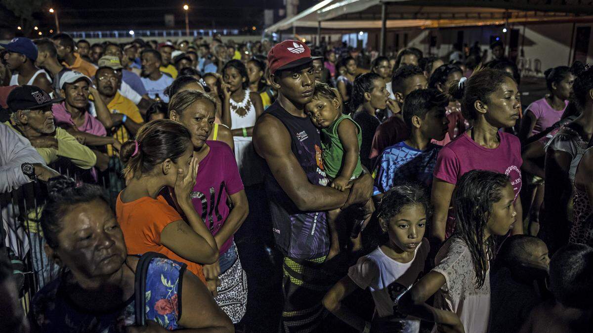 Decenas de inmigrantes venezolanos esperan para recibir comida entregada por militares brasileños, en Boa Vista, Brasil, el 4 de abril de 2018.