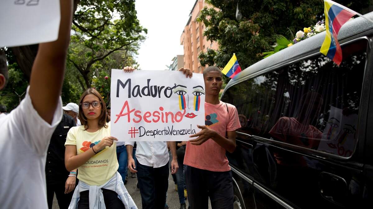 Manifestantes denuncian al régimen de Nicolás Maduro mientras acompañan la carroza fúnebre que traslada los restos del concejal de la oposición Fernando Albán, el miércoles en Caracas. Albán fue detenido por el servicio de inteligencia de Venezuela, y apareció muerto el lunes en circunstancias sospechosas. Representantes de la oposición dicen que fue asesinado mientras estaba bajo custodia policial.