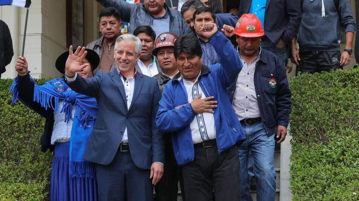 El presidente boliviano, Evo Morales (centro), y el vicepresidente Álvaro García Linera (c-i), saludan a simpatizantes a su llegada a las oficinas del Tribunal Supremo Electoral el 28 de noviembre, en La Paz. La dupla Morales-García Linera se presentará por cuarta vez a los comicios nacionales gracias a un fallo de 2017 del Tribunal Constitucional que los habilita a la reelección indefinida.