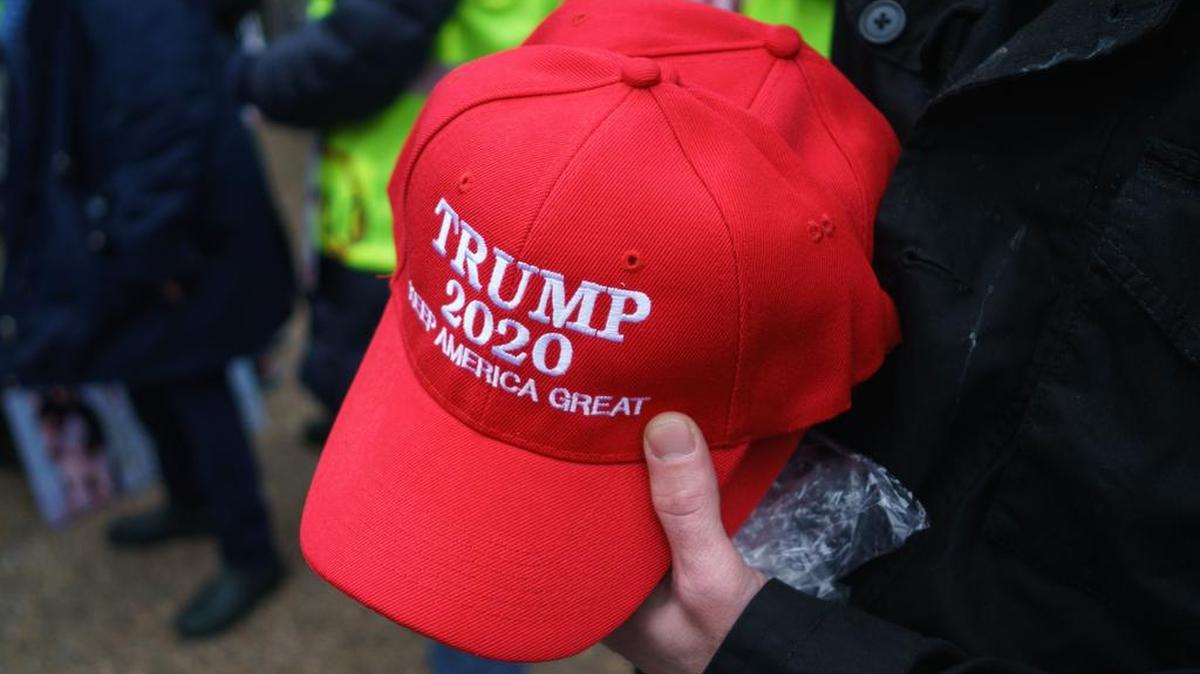 Un hombre muestra gorras con el eslogan “Trump 2020”, durante un acto político de apoyo al presidente Donald Trump, el 23 de febrero, en Washington.