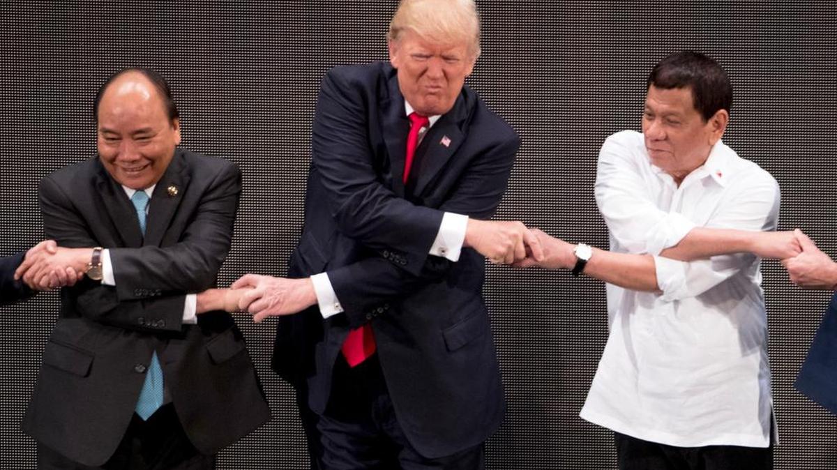 El presidente Donald Trump realiza el “apretón de manos de la ASEAN” con sus homólogos, el vietnamita Tran Dai Quang (izq), y el filipino Rodrigo Duterte, durante la ceremonia de apertura de la cumbre, en Manila, Filipinas.