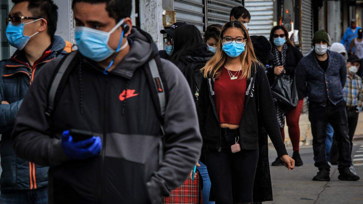 Gente con mascaras y manteniendo el distanciamiento social hacen fila el 5 de mayo de 2020 para entrar en una tienda en la avenida 5 en Sunset Park, el vecindario en Brooklyn con una de las comunidades más grandes de mexicanos y otros hispanos de Nueva York.