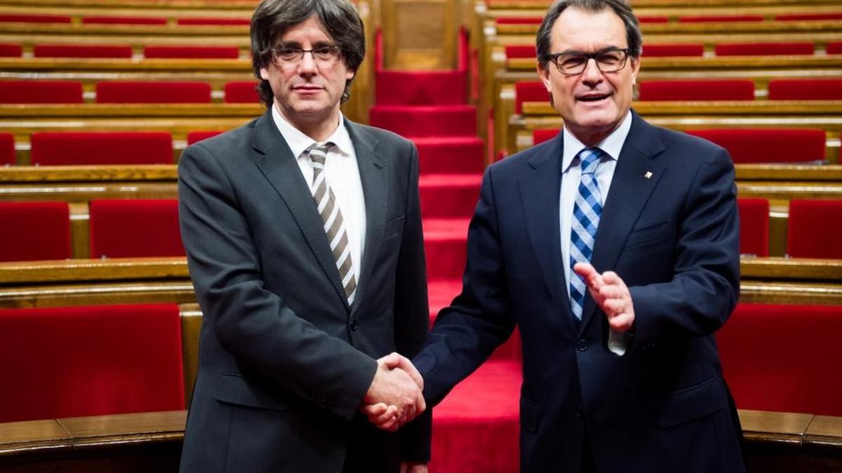 El presidente saliente, Artur Mas, saluda al líder de Cataluña, Carles Puigdemont (izq.), después de su elección como nuevo presidente, el domingo 10, en Barcelona.