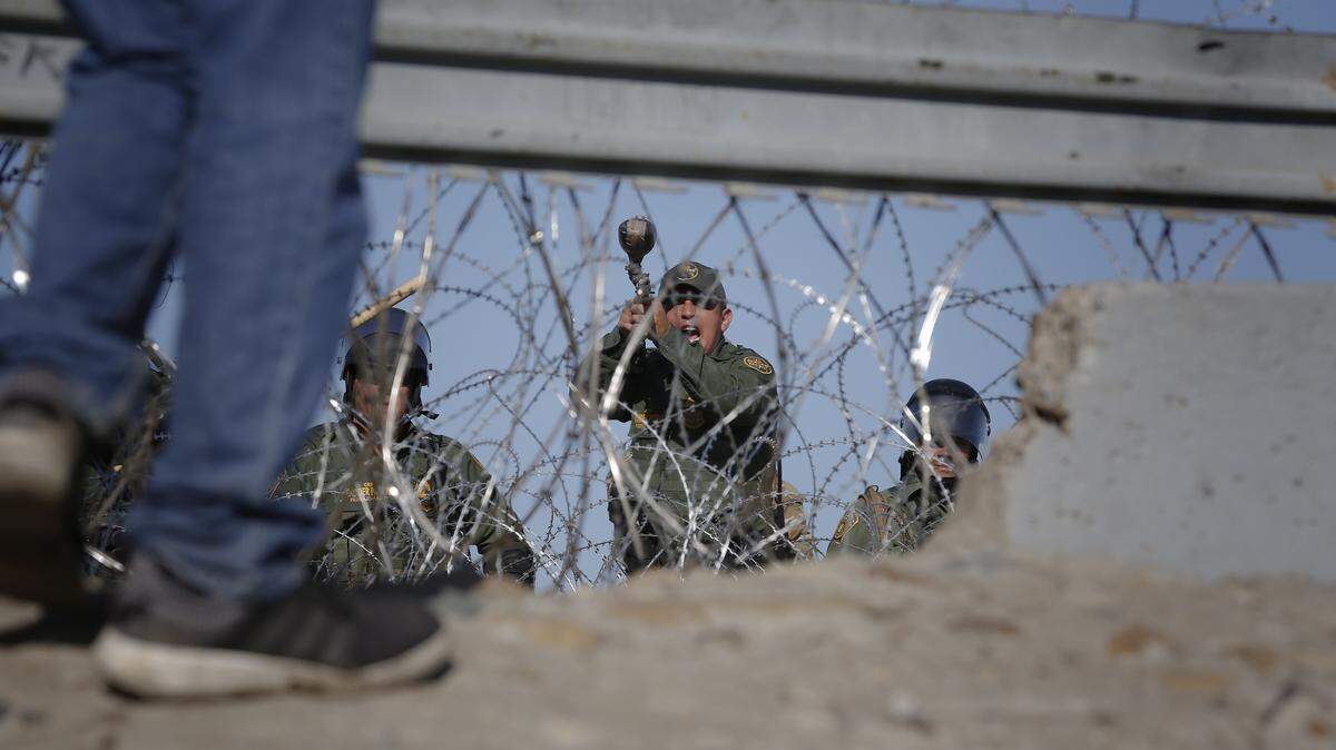 Un agente de la Patrulla de Fronteras de EEUU grita instrucciones a inmigrantes para que se alejen de un punto fronterizo entre México y Estados Unidos.
