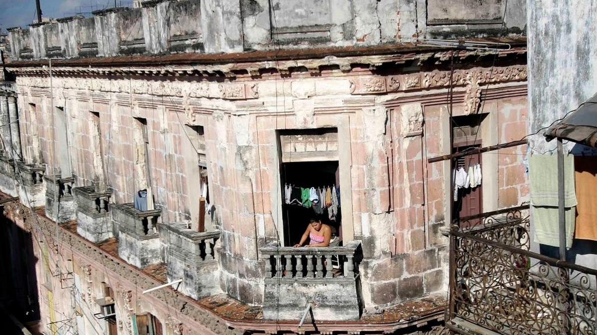 Una mujer mira desde un balcón de un edificio en La Habana Vieja.