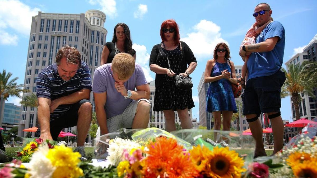 Frente al Centro de Artes Escénicas Dr. Phillips, en un memorial improvisado a las víctimas de la matanza cometida en Orlando el domingo, Richie Compton (izq.) y Erik Winger rinden tributo a su amigo Shane Tomlinson, asesinado en el sangriento tiroteo.
