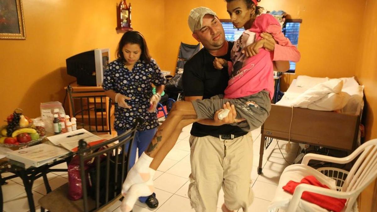 Linda Pérez en brazos de su padre, Fernando Izquierdo, en su casa en Homestead, en enero del 2014. Pérez se sometió a una cirugía de aumento de pechos en una clínica de Coral Gables en agosto del 2013. La joven de 18 años estuvo en coma debido a complicaciones del procedimiento, que le provocaron daños cerebrales y en el corazón.