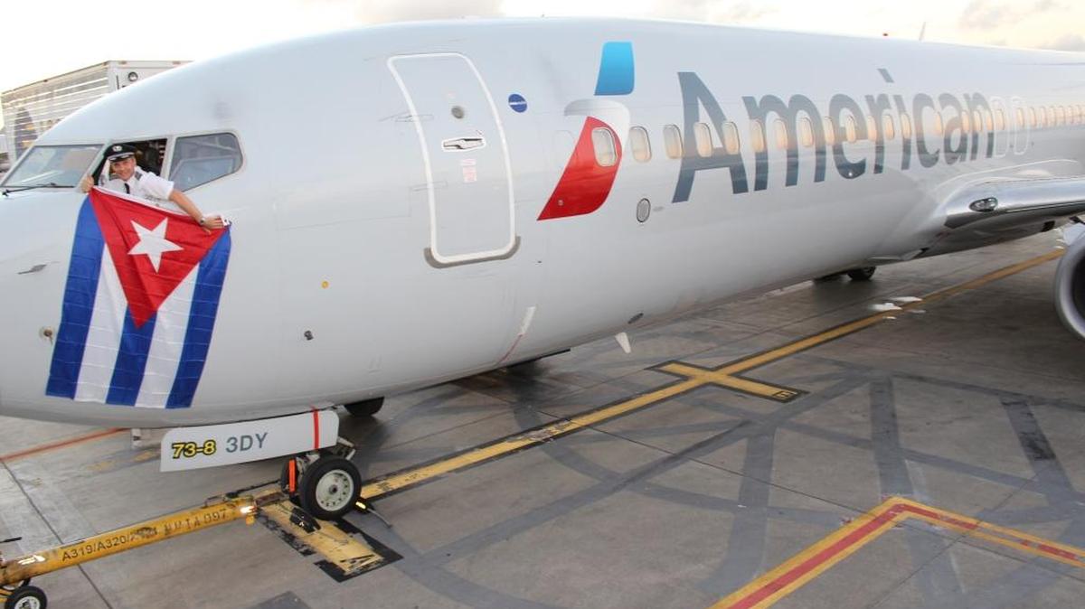 Kevin Mase, de American Airlines, saca una bandera cubana por la ventanilla de un AA Boeing 737, en diciembre del 2015, al anunciarse que Cuba y EEUU llegaron a un acuerdo para restablecer vuelos comerciales.