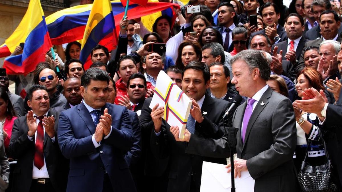 El presidente del Senado, Mauricio Lizcano, recibe del presidente de Colombia, Juan Manuel Santos (derecha) el acuerdo de paz con las FARC, en Bogotá, el 25 de agosto.