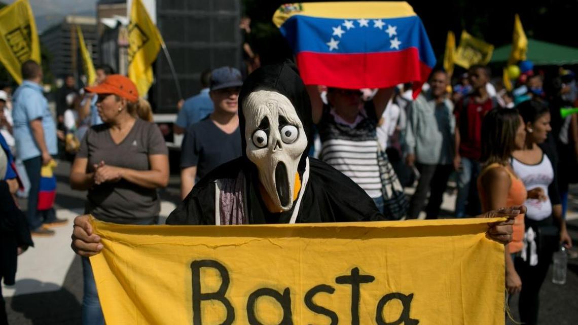 Un manifestante enmascarado lleva una pancarta que dice “Basta” en una protesta contra el gobernante Nicolás Maduro en Caracas, Venezuela, el miércoles 26.