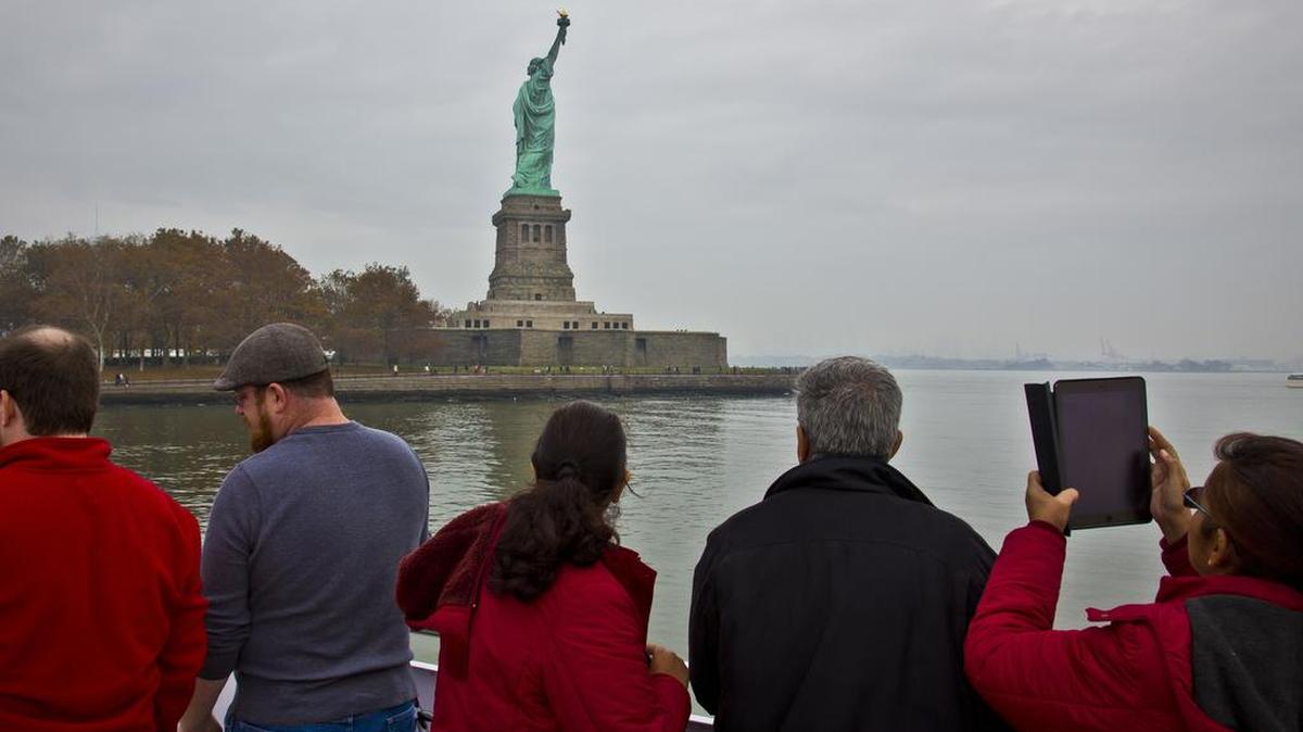 Visitantes observan la Estatua de la Libertad, en Nueva York. La cantidad de turistas que vienen a Estados Unidos ha bajado casi el 4 por ciento.