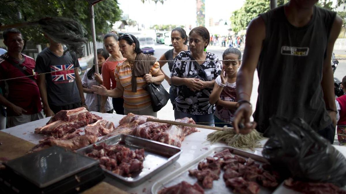 Varias personas compran carne en un puesto callejero en Caracas, el 10 de diciembre. Venezuela sufre una hiperinflación.
