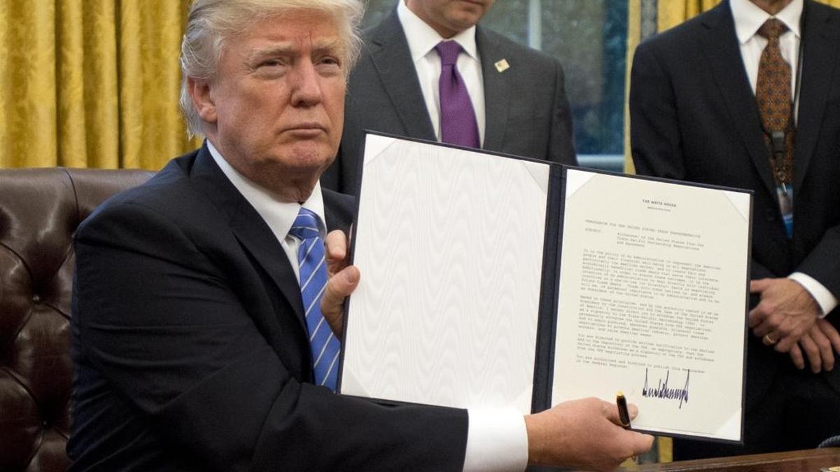 El presidente Donald Trump muestra el documento que confirma la retirada de EEUU del Acuerdo TransPacífico (TPP) después de firmarlo en la Oficina Oval de la Casa Blanca el 23 de enero.