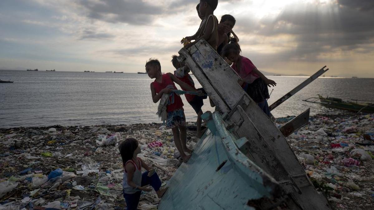Varios niños juegan en una playa de las Filipinas, cerca de Manila, cubierta por desechos plásticos.
