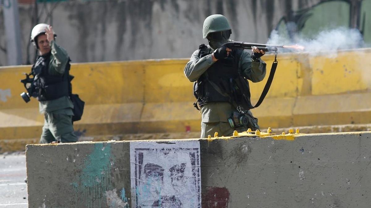 Miembros de las fuerzas de seguridad del gobierno de Maduro disparan a manifestantes durante una protesta en Caracas.