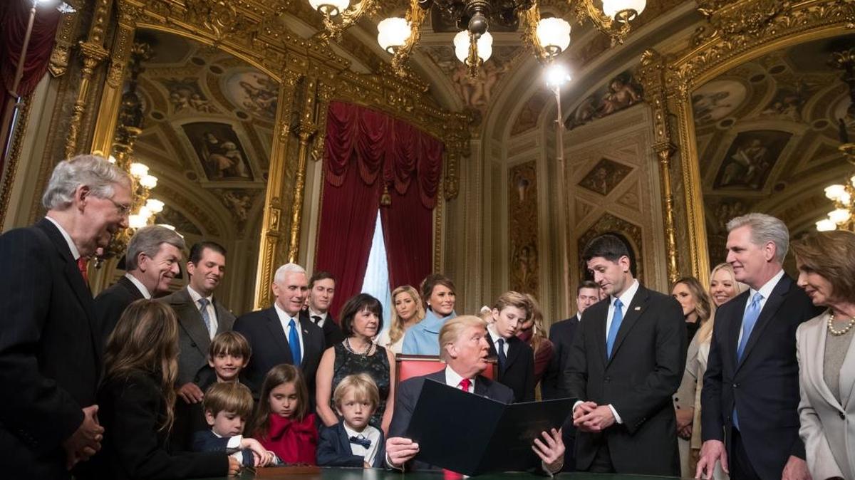 El presidente Donald Trump se dirige al presidente de la Cámara, Paul Ryan, mientras firma las nominaciones al gabinete, junto a miembros del Congreso y familia, en la Sala presidencial del Senado, en el Capitolio de Washington, el 20 de enero del 2017.