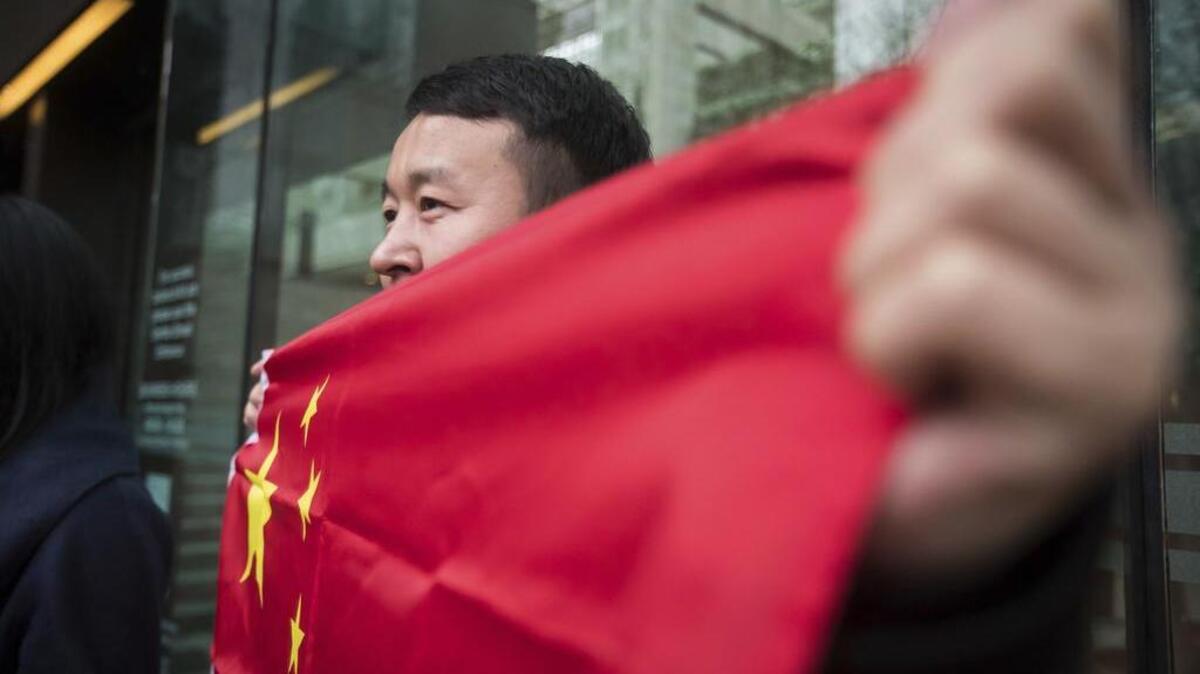 Un hombre sostiene una bandera china afuera de la Corte Suprema de British Columbia en protesta por la detención de Meng Wanzhou, la heredera de Huawei, una enorme empresa china de telecomunicaciones que vende más celulares que Apple, el 11 de diciembre 2018.