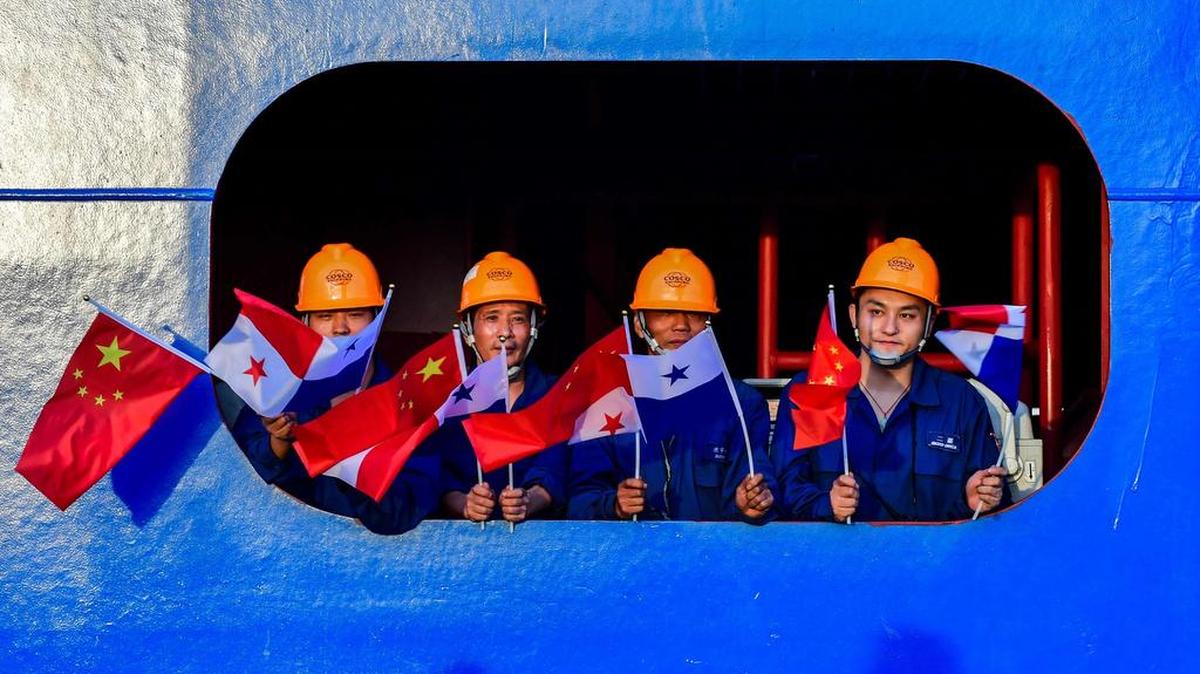 Miembros de la tripulación del buque portacontenedores Chinese Cosco Shipping Rose ondean banderas de China y Panamá antes del encuentro entre los líderes de ambos países, el 3 de diciembre en el Canal de Panamá.