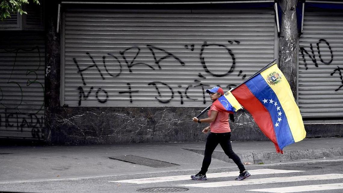 Una mujer lleva una bandera de Venezuela durante una jornada de huelga nacional en Caracas.