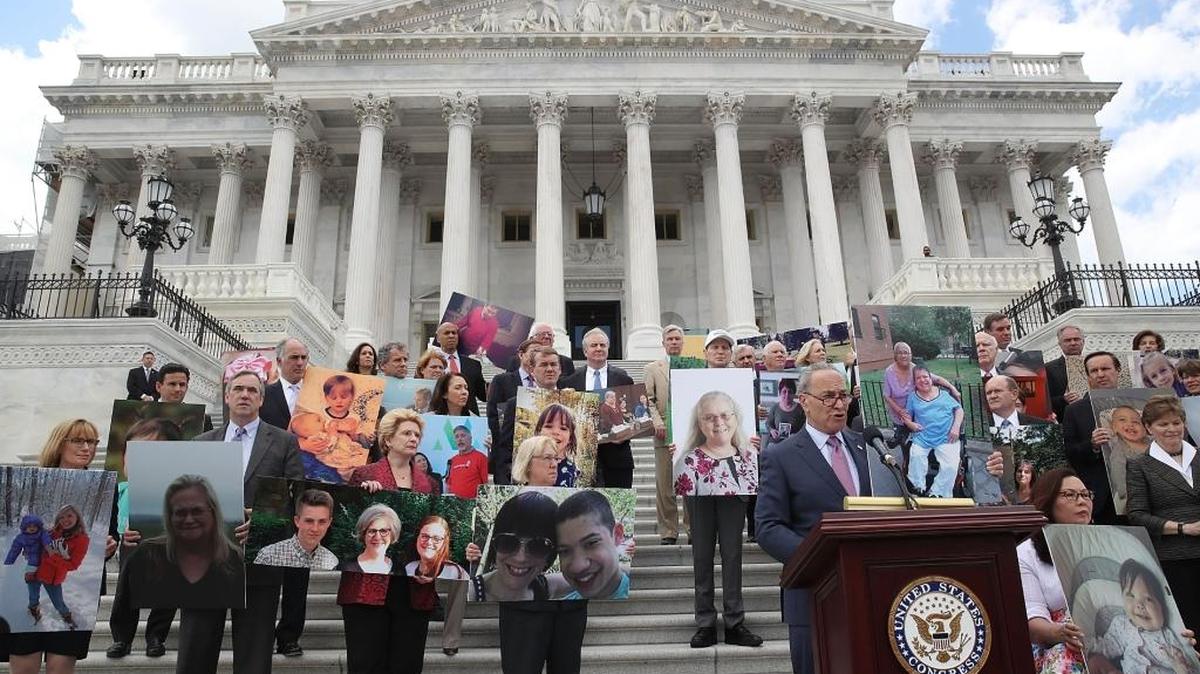 El líder de la minoría en el Senado, Chuck Schumer (D-NY) habla flanqueado por demócratas del Senado sosteniendo fotos de personas que perderán su cobertura de salud bajo el plan de los republicanos, durante una conferencia de prensa en el Capitolio en Washington DC, el 27 de junio.