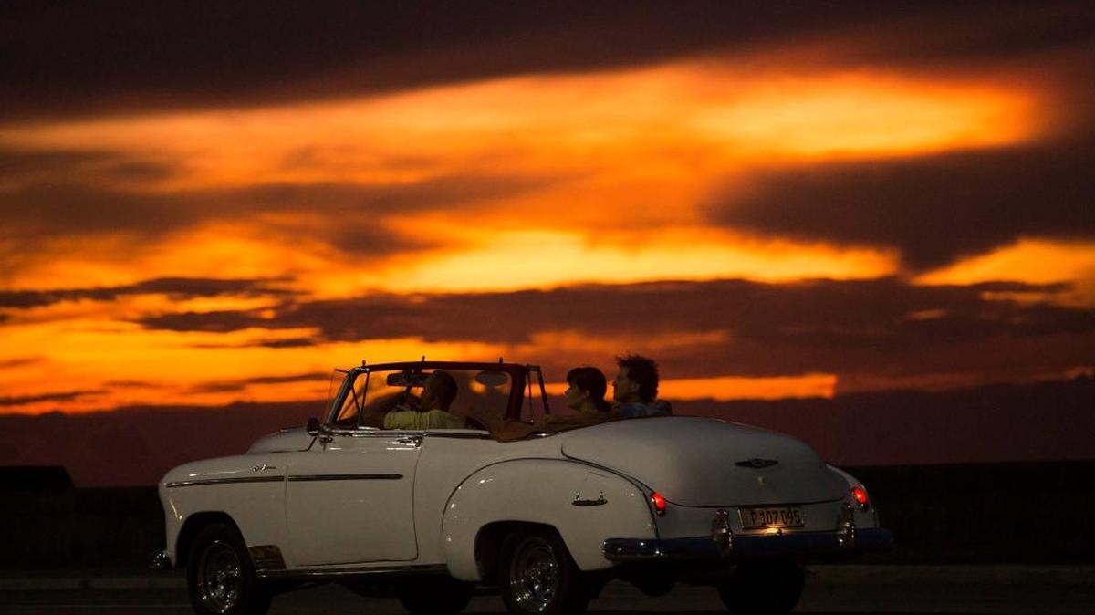 Turistas recorren el malecón en un automóvil clásico norteamericano.