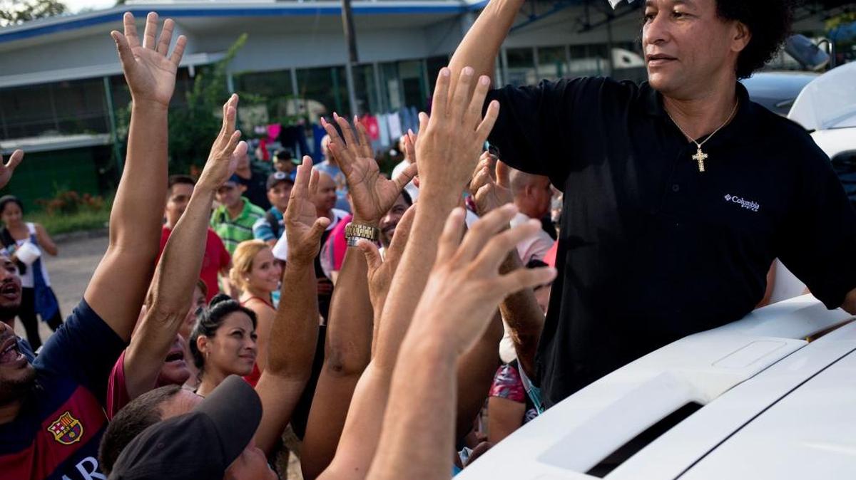 Un costarricense entrega donaciones de ropa a migrantes cubanos en el exterior de la oficina de inmigración en Peñas Blancas, Costa Rica, el 17 de noviembre. Ocho mil cubanos viajarán a Estados Unidos para acogerse a la Ley de Ajuste Cubano.