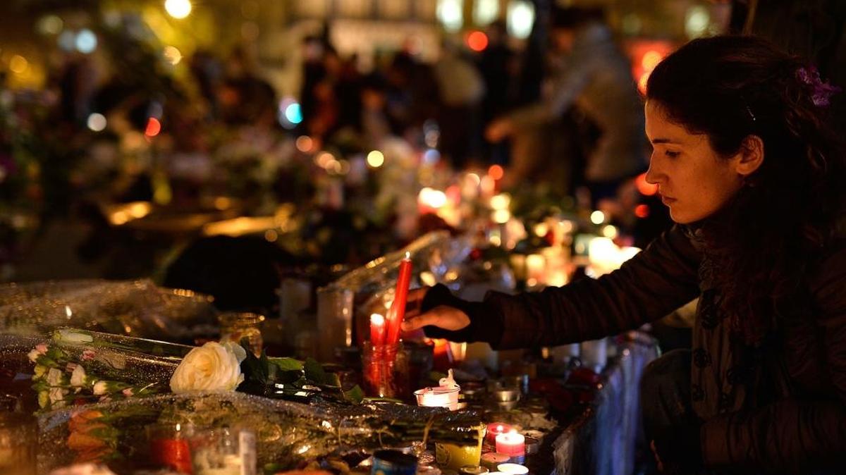 Una mujer enciende una vela en la Plaza República en París, por las víctimas de los actos terroristas del viernes 13 de noviembre.
