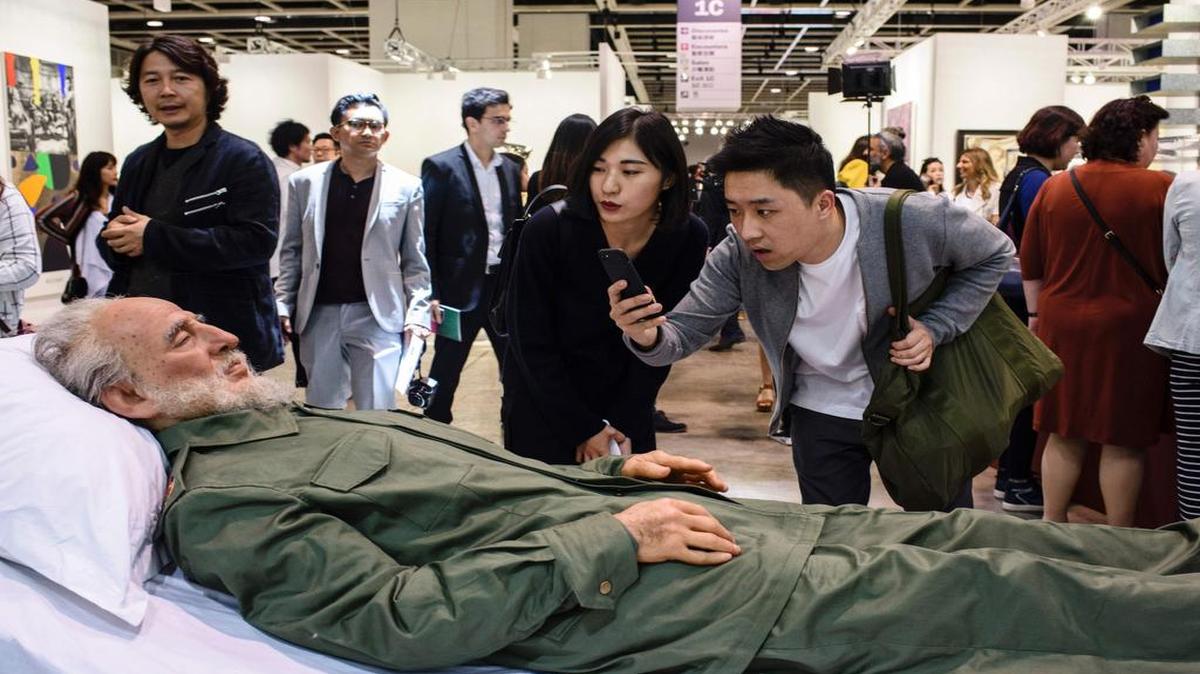 Un par de visitantes toma fotos de una representación artística de Fidel Castro realizada por el artista chino Shen Shaomin en Hong Kong.