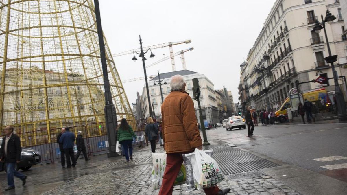Un transeúnte pasea frente a la Puerta del Sol en el centro de Madrid, una ciudad que, por su configuración y numerosos cafés, permite una vida social activa, especialmente para las personas mayores.