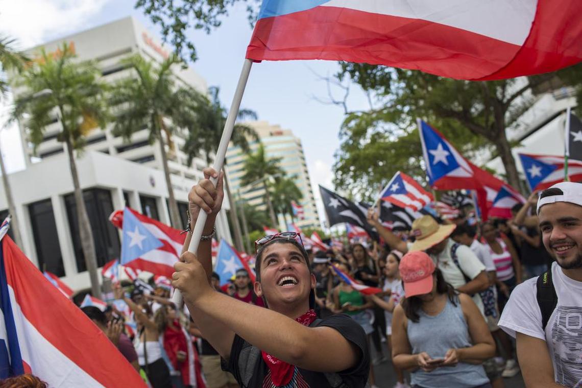 People wave Puerto Rican national flags as they march to celebrate the resignation of Gov. Ricardo Rossello who announced overnight that he is resigning Aug. 2 after weeks of protests over leaked obscene, misogynistic online chats, in San Juan, Puerto Rico, Thursday, July 25, 2019.(AP Photo/Dennis M. Rivera Pichardo)