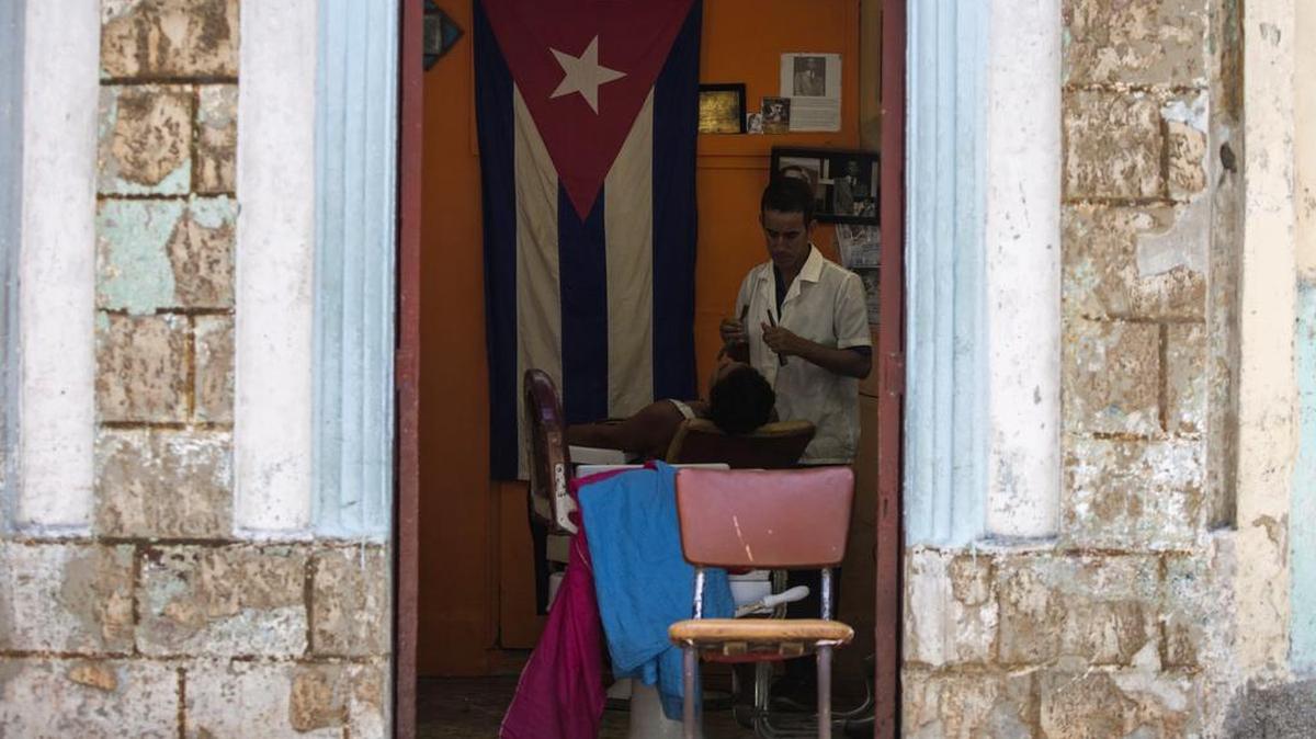 Un barbero afeita a un cliente en su negocio privado con licencia en La Habana.