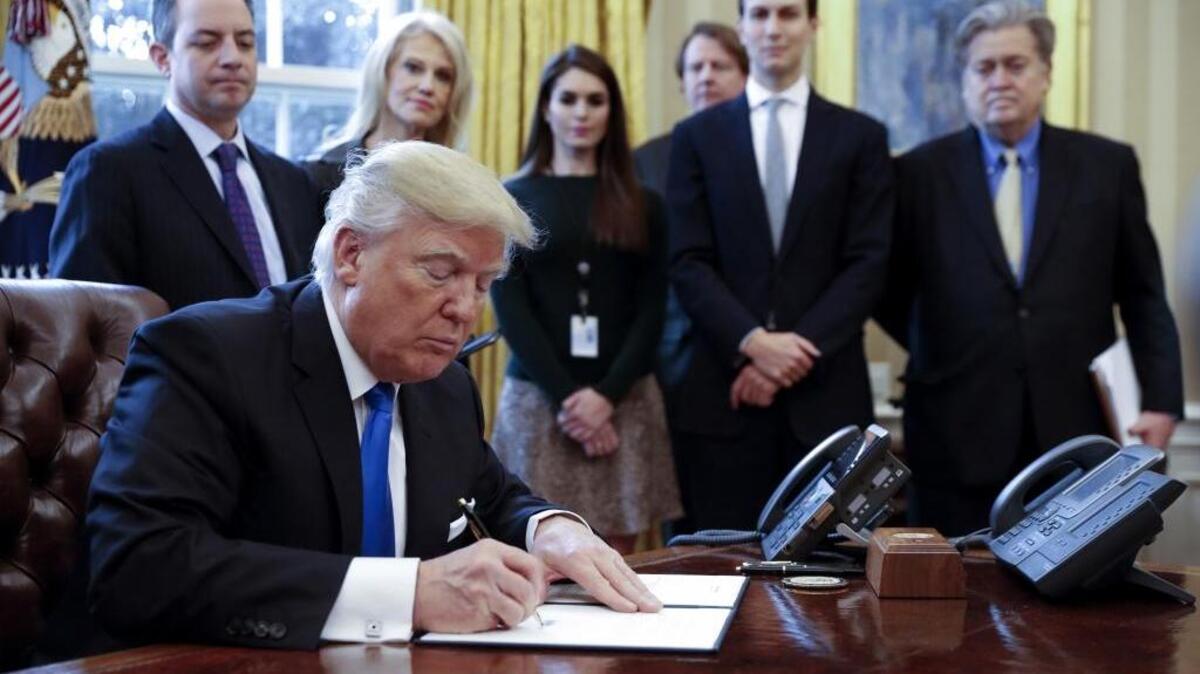 El presidente Donald Trump firma órdenes ejecutivas sobre la industria petrolera el 24 de enero en la Casa Blanca. Su asesor recién despedido, Steve Bannon, lo observa a la derecha.