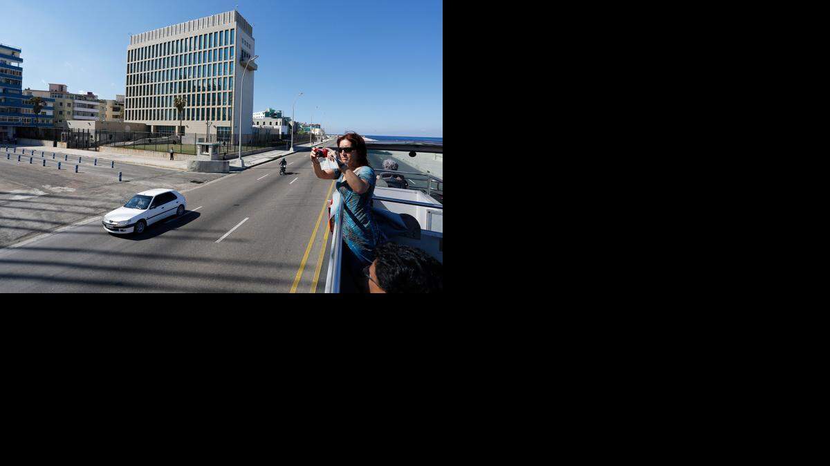 
Una turista toma fotos desde un autobús de dos pisos al pasar cerca del edificio de la Oficina de Intereses de Estados Unidos en La Habana, el pasado 18 de diciembre, un día después del anuncio de la normalización de las relaciones.
