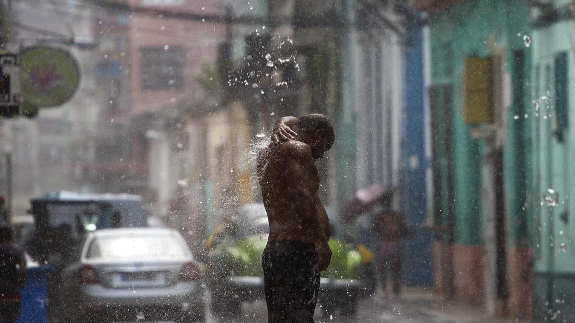 Un hombre se baña con el agua que cae de un desagüe, en el medio de una tormenta en La Habana.
