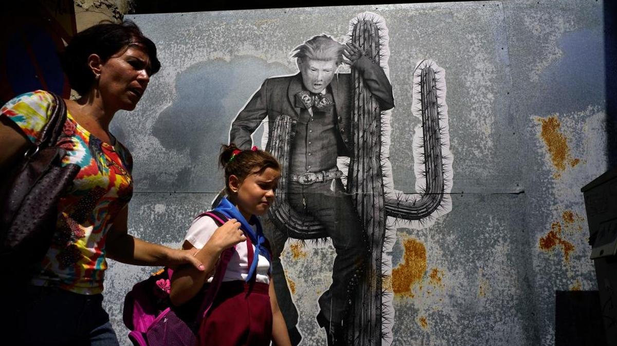 Una mujer y su hija pasan frente a un mural que representa al presidente Donald Trump, en una calle de La Habana, el 16 de junio.