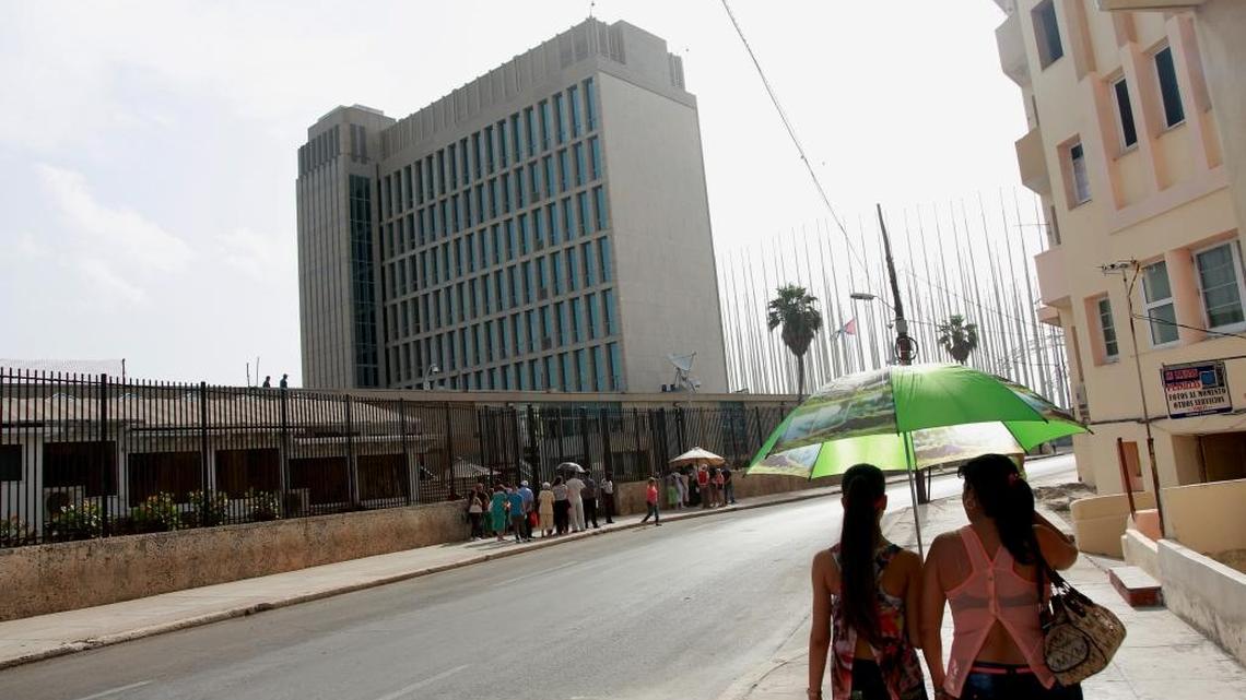 Dos mujeres observan la embajada de Estados Unidos en La Habana, donde varias personas hacen fila para solicitar visa, el pasado julio.