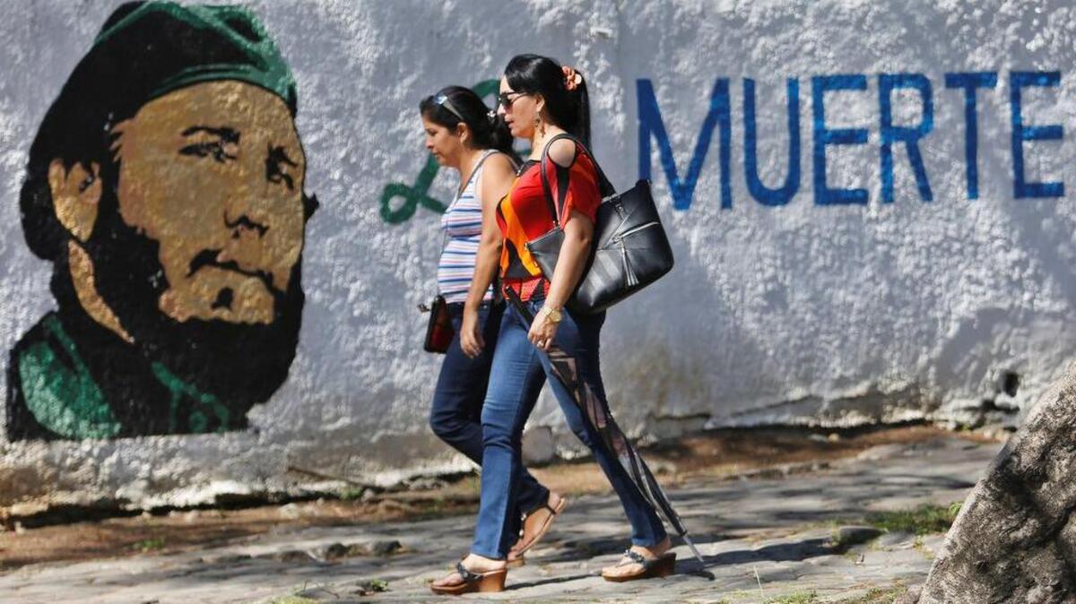 Dos mujeres pasan caminando este miércoles frente a un graffiti de Fidel Castro en un parque de La Habana, el 24 de abril. Castro siempre tuvo interés en intervenir en Venezuela y lo intentó con la invasión de Machurucuto en mayo de 1967.