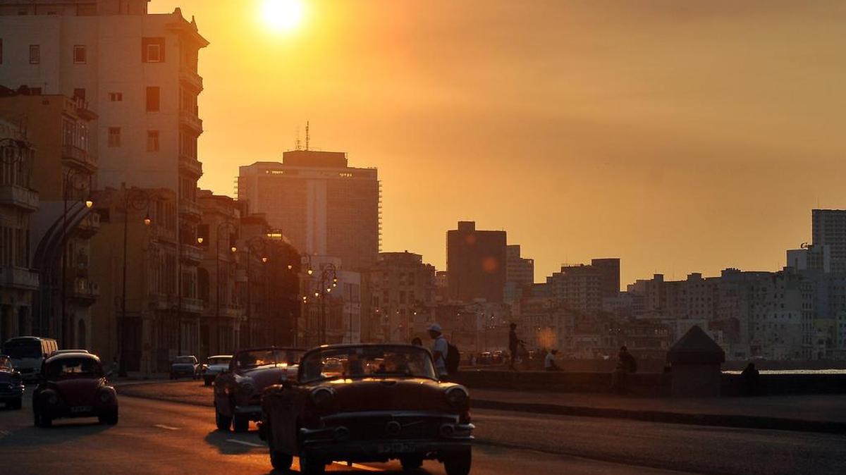Varios autos clásicos pasan por una zona del malecón, mientras cae el sol, el 4 de marzo en La Habana.