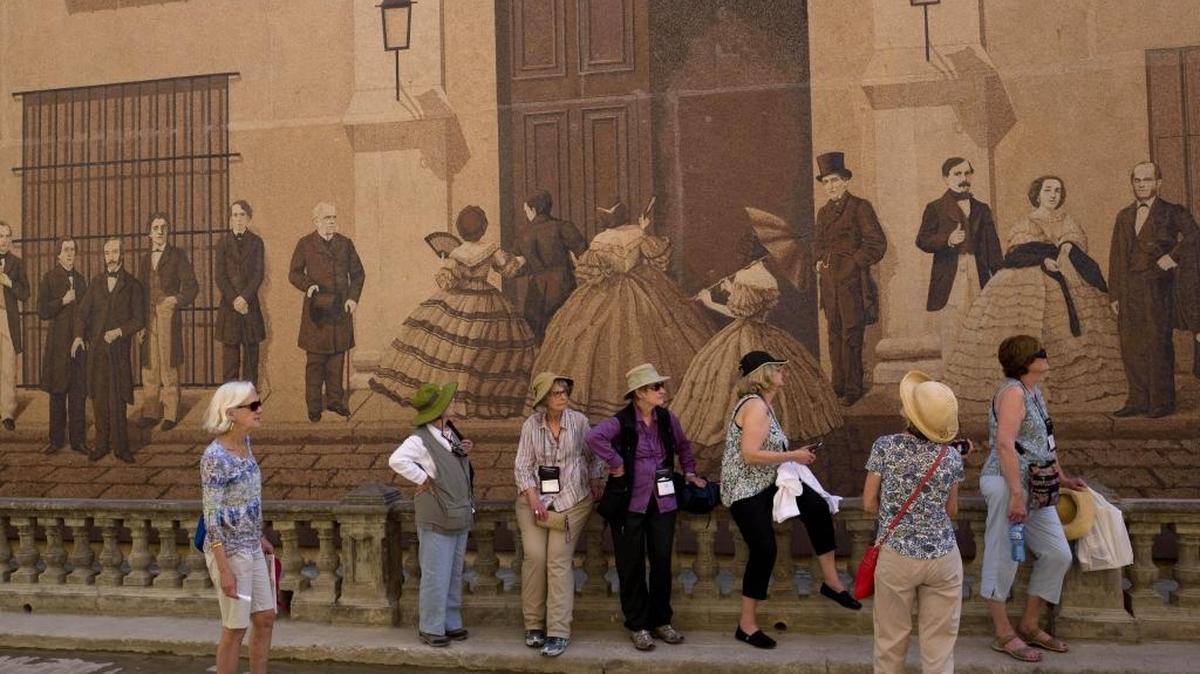 Un grupo de personas espera en una fila frente a un mural en La Habana Vieja, el 17 de marzo.