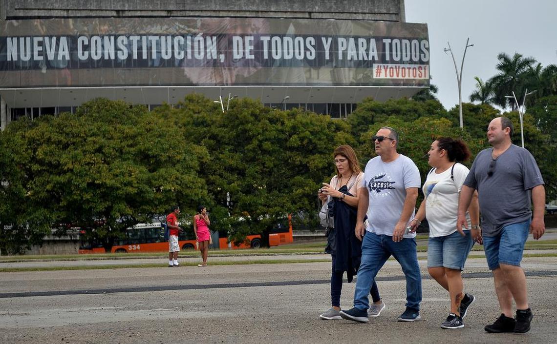 A group of tourists walk near a government billboard in Havana that reads: ‘’A new Constitution of all and for all.”