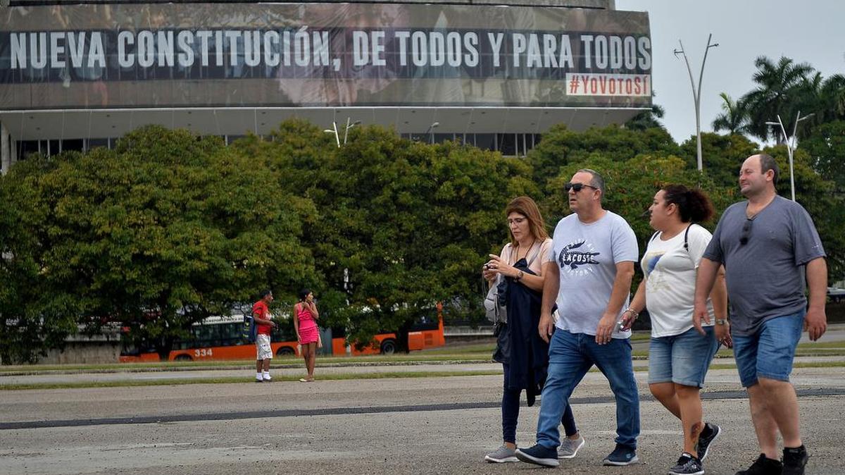 Unos turistas caminan frente a un anuncio del gobierno a favor de la nueva Constitución, el 13 de febrero en La Habana.