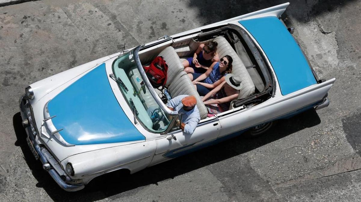 Turistas pasean en un auto norteamericano clásico en La Habana.