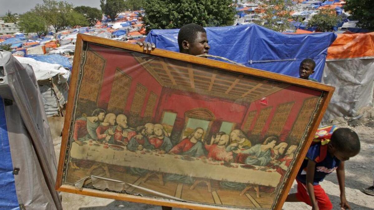 El cuadro “La última cena” es una de las reproducciones artísticas más comunes en el mundo. En la foto, un joven lleva un afiche de la famosa escena religiosa a su tienda, en un campamento de sobrevivientes del terremoto en Haití, en marzo del 2010.