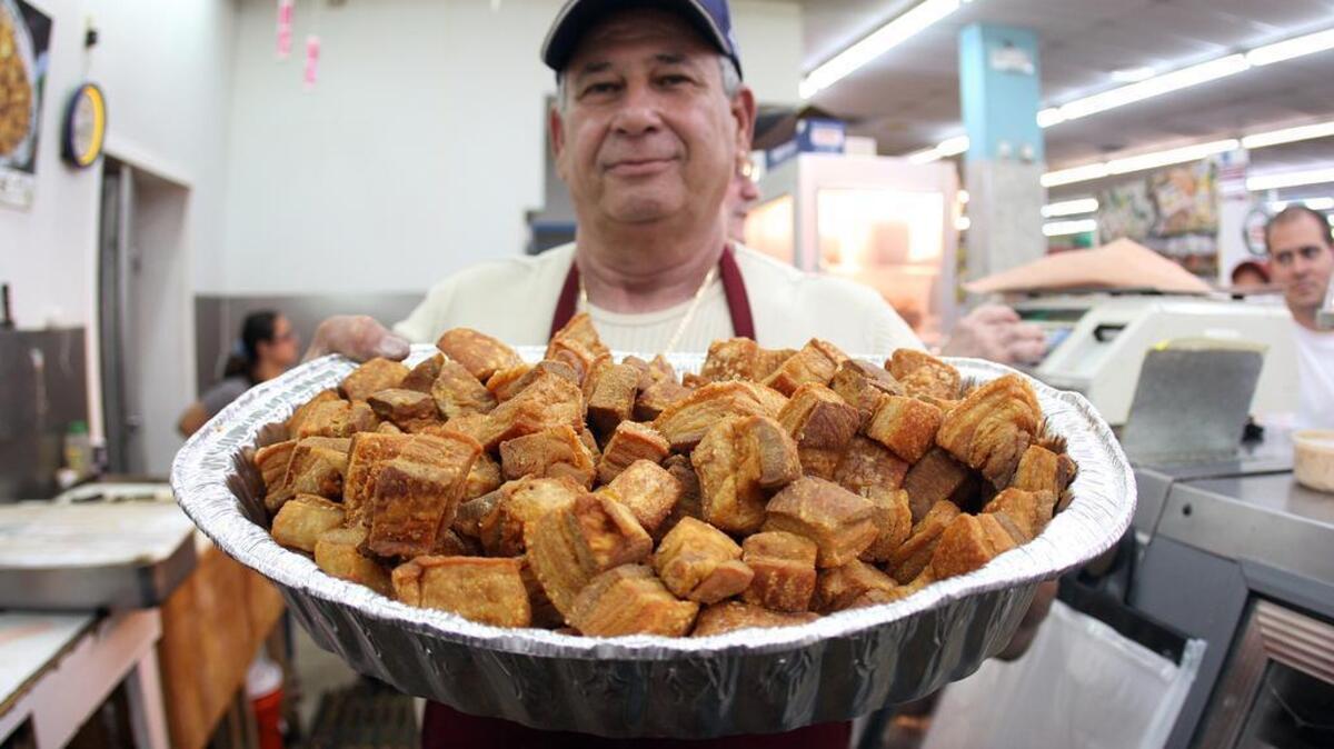 Antonio Martínez lleva una bandeja de chicharrones recién hechos por él en el mercado La Bodega, en 2010. Platos de la cocina criolla sazonaron las mesas de Nochebuena de los cubanos en Miami.