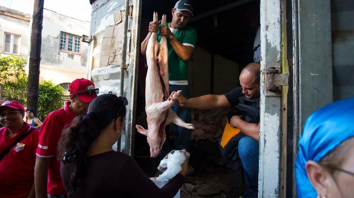 Una mujer compra un puerco en un mercado al aire libre, administrado por el estado, el 30 de diciembre en La Habana.